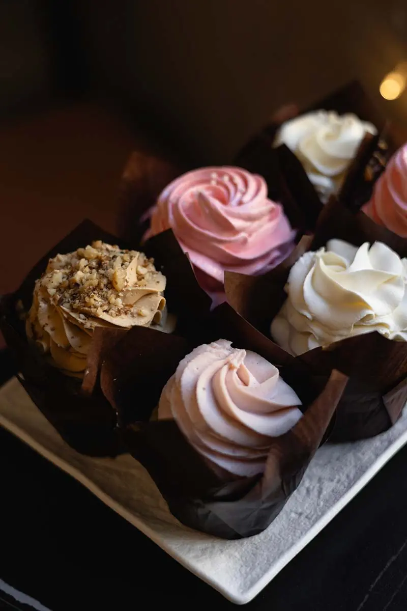 Асортимент апетитних капкейків з різними видами крему в кав'ярні Muffin Cafe.